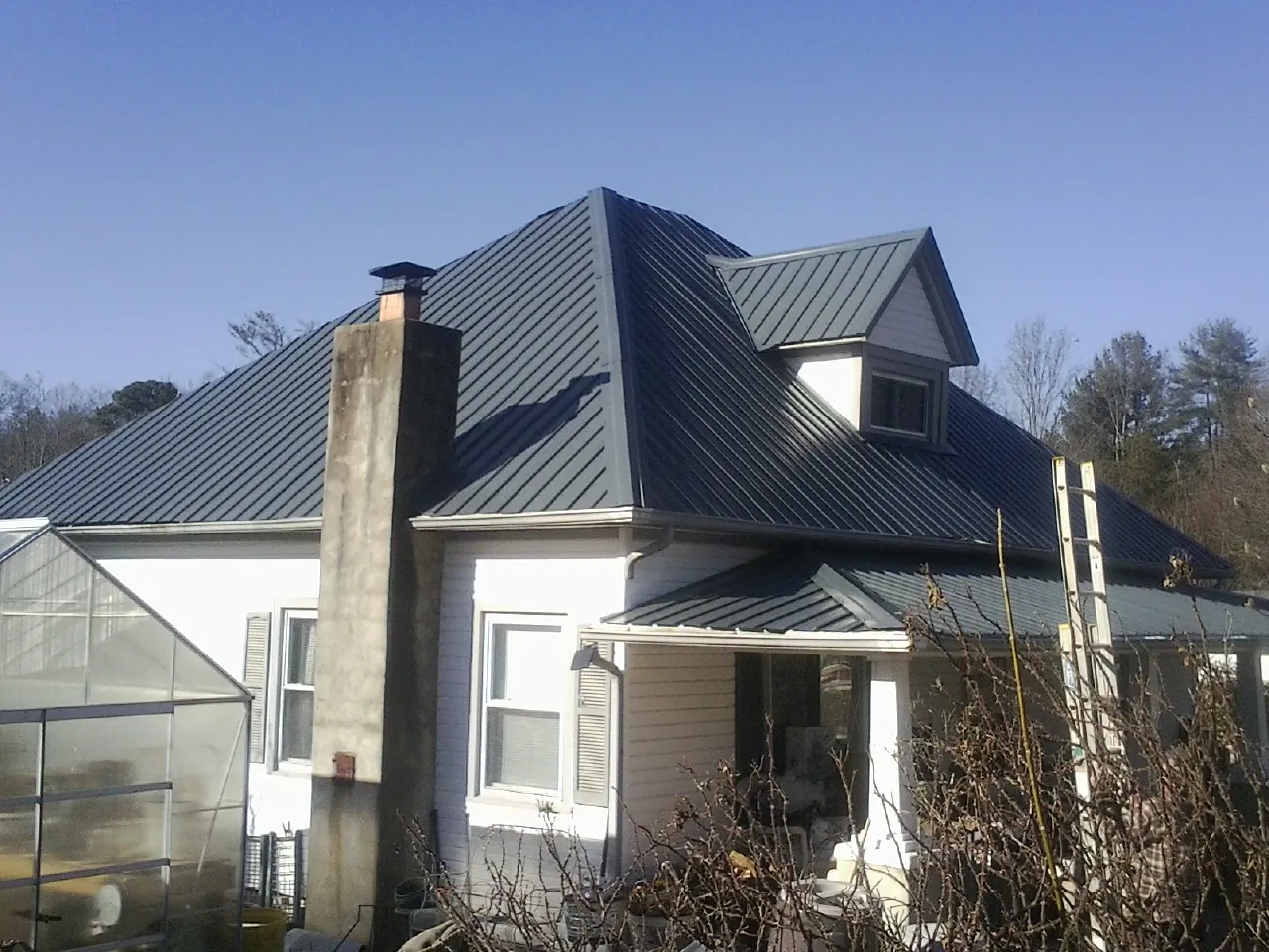 Dark blue standing seam metal roof on a white farmhouse with dormer — Slate & Tile Roof Repair by Roofing Brothers in Blountsville