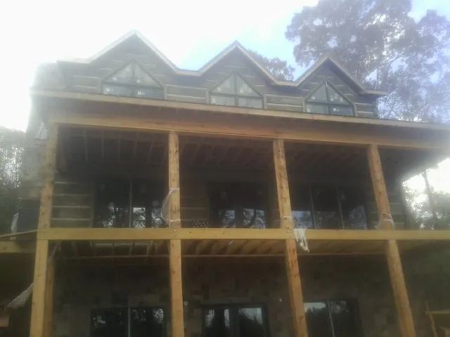 Dormers and porch framing on a large log home under construction — Roof Coating work by our crew in Blountsville