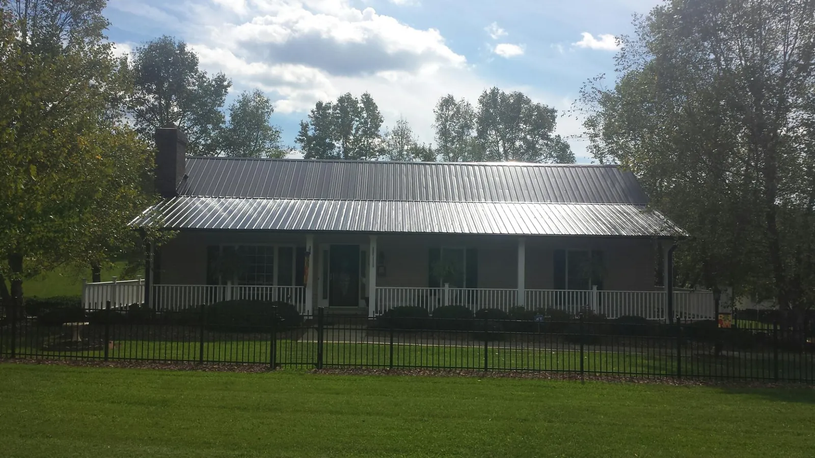 Gray metal roof on a brick ranch with a full width front porch — Gutter Guard Installation work by our crew in Blountsville