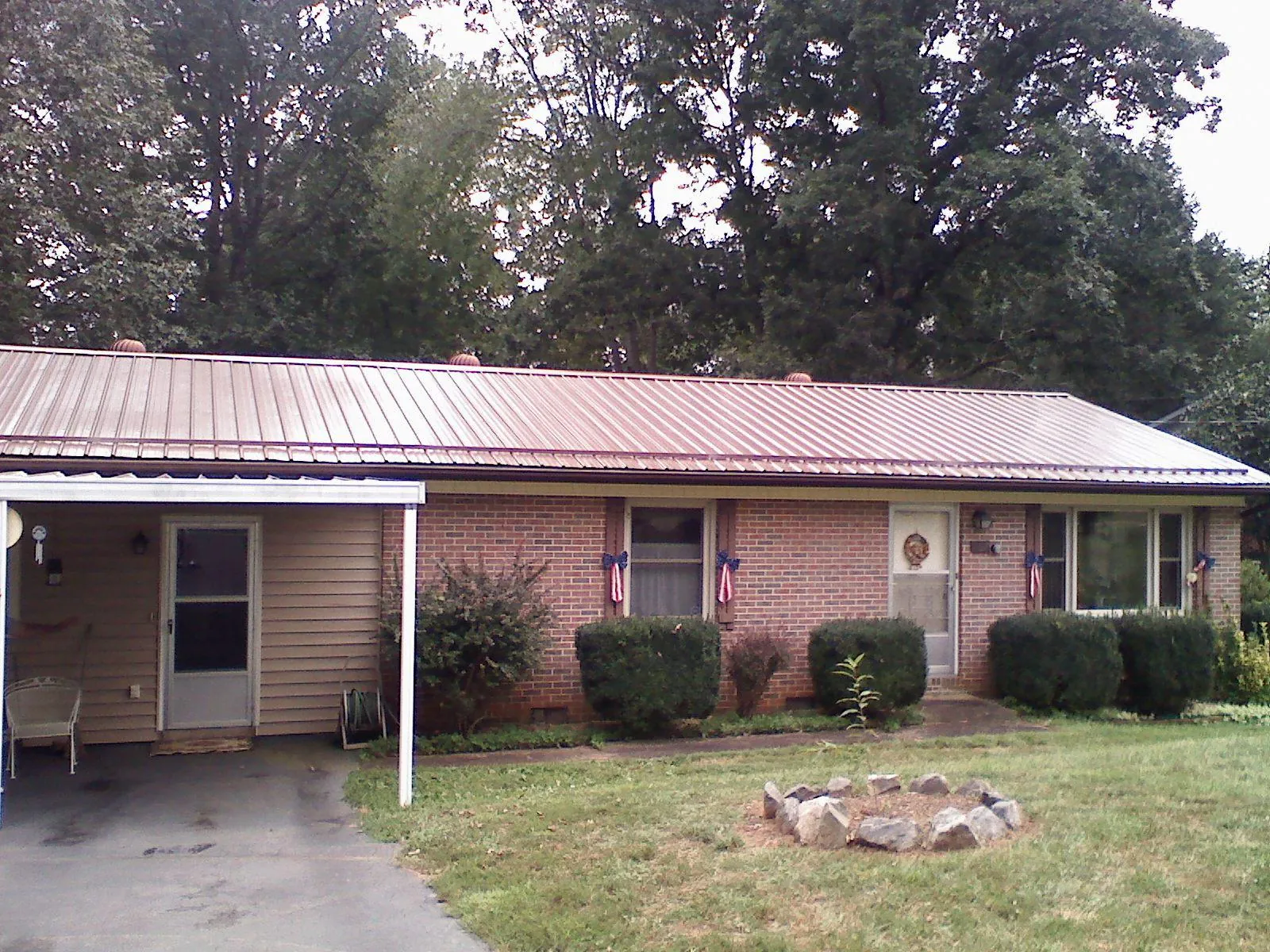 Bronze metal roof and carport on a brick ranch home — Roof Repair work by our crew in Blountsville