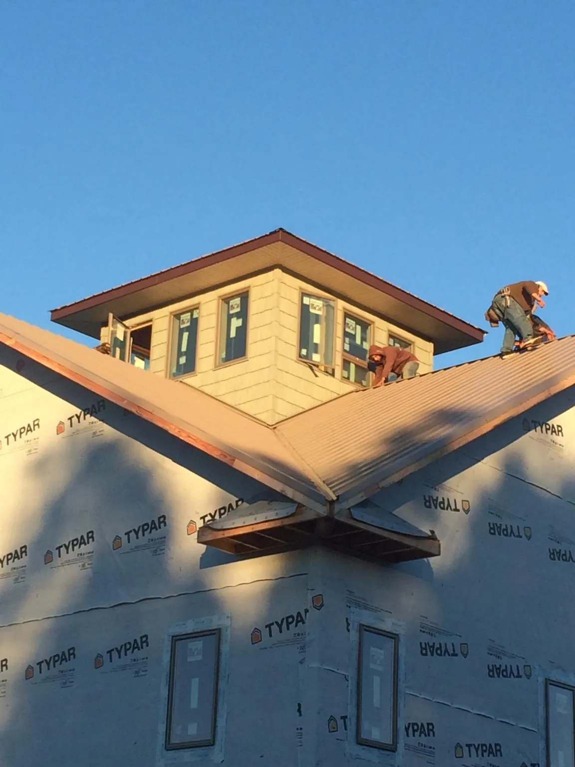 Roofers working around a rooftop cupola on a new metal roof at sunset — Roof Waterproofing in Blountsville by Roofing Brothers